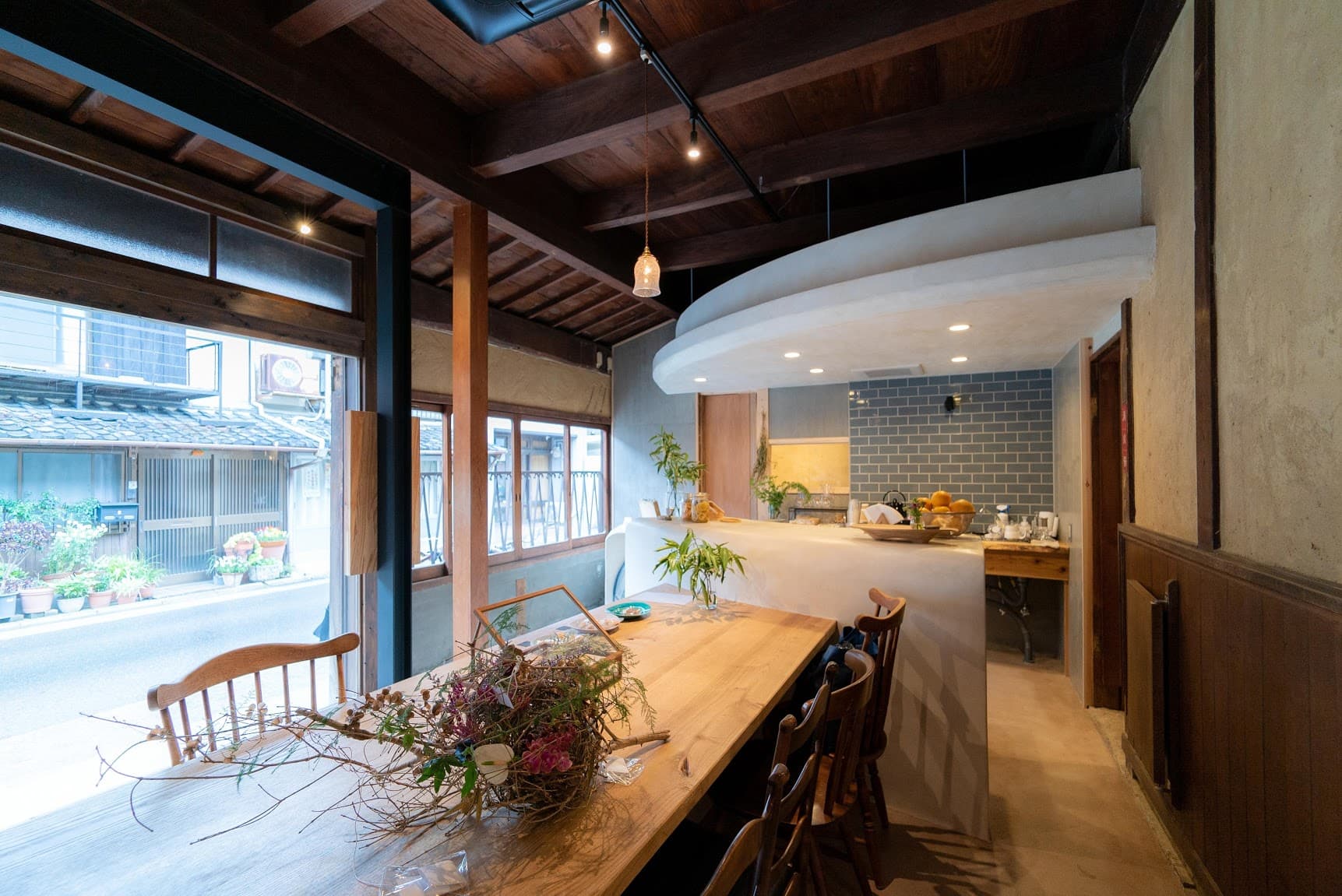 The earthen-floor cafe space with a long table and fresh flowers, looking out to the streets of Sumoto
