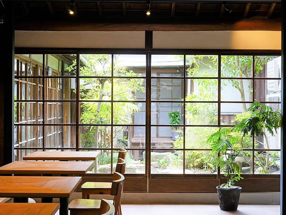 The courtyard seen through latticed doors, with wooden table seating in the foreground